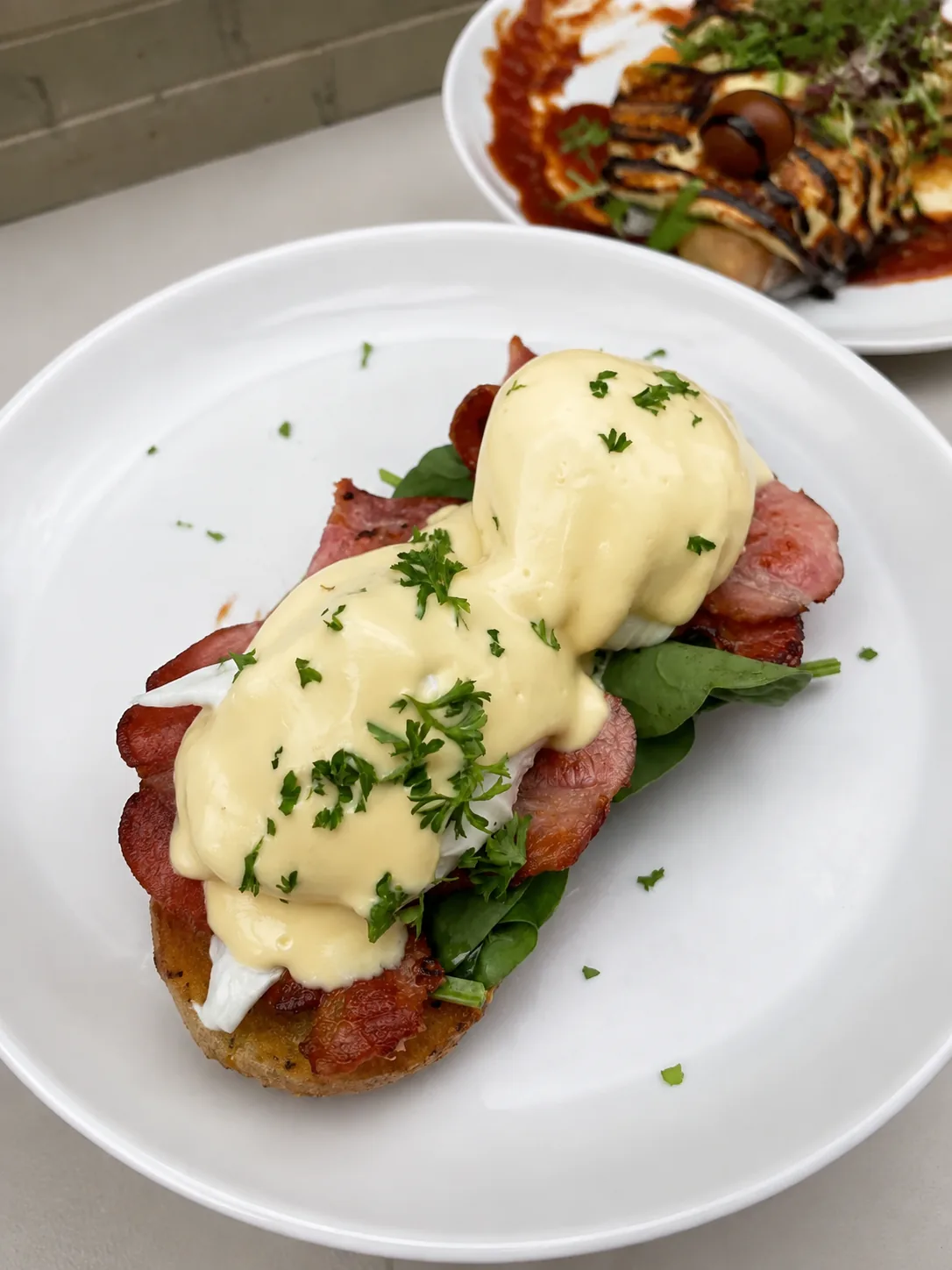 A plated breakfast with eggs, bacon and hollandaise