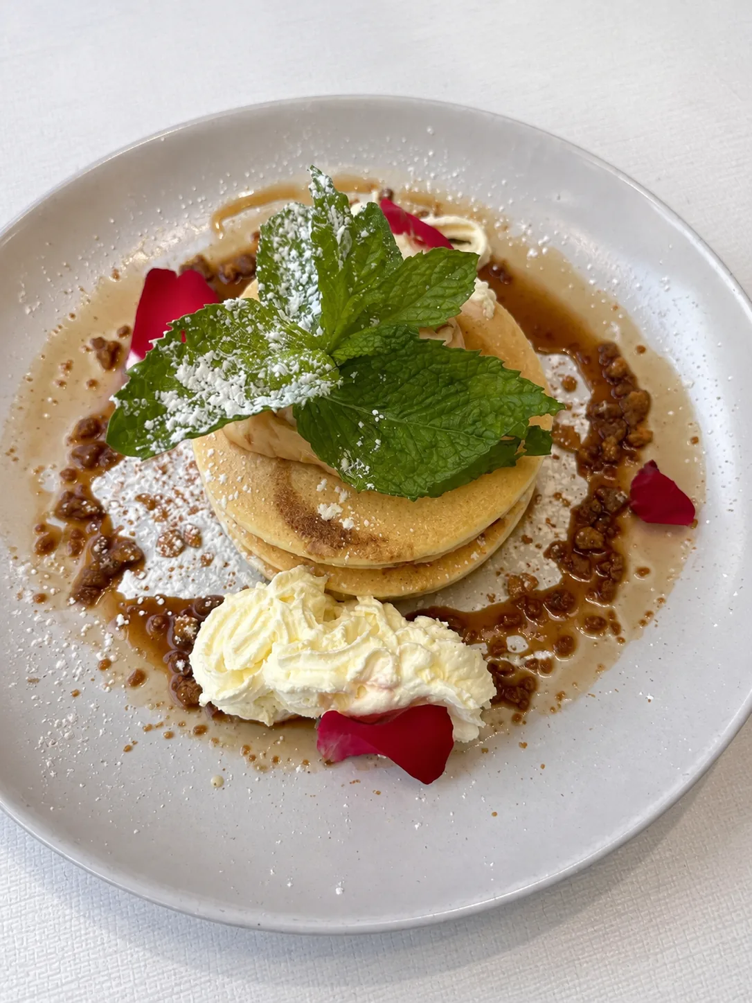 A stack of pancakes with cream and mint